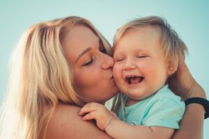 mother kissing the smiling baby